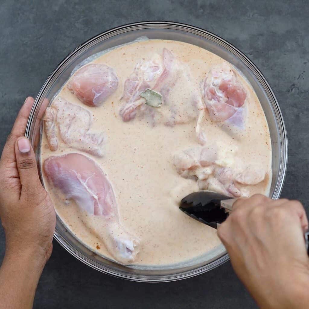 Soaking chicken thighs, and legs into the buttermilk mixture