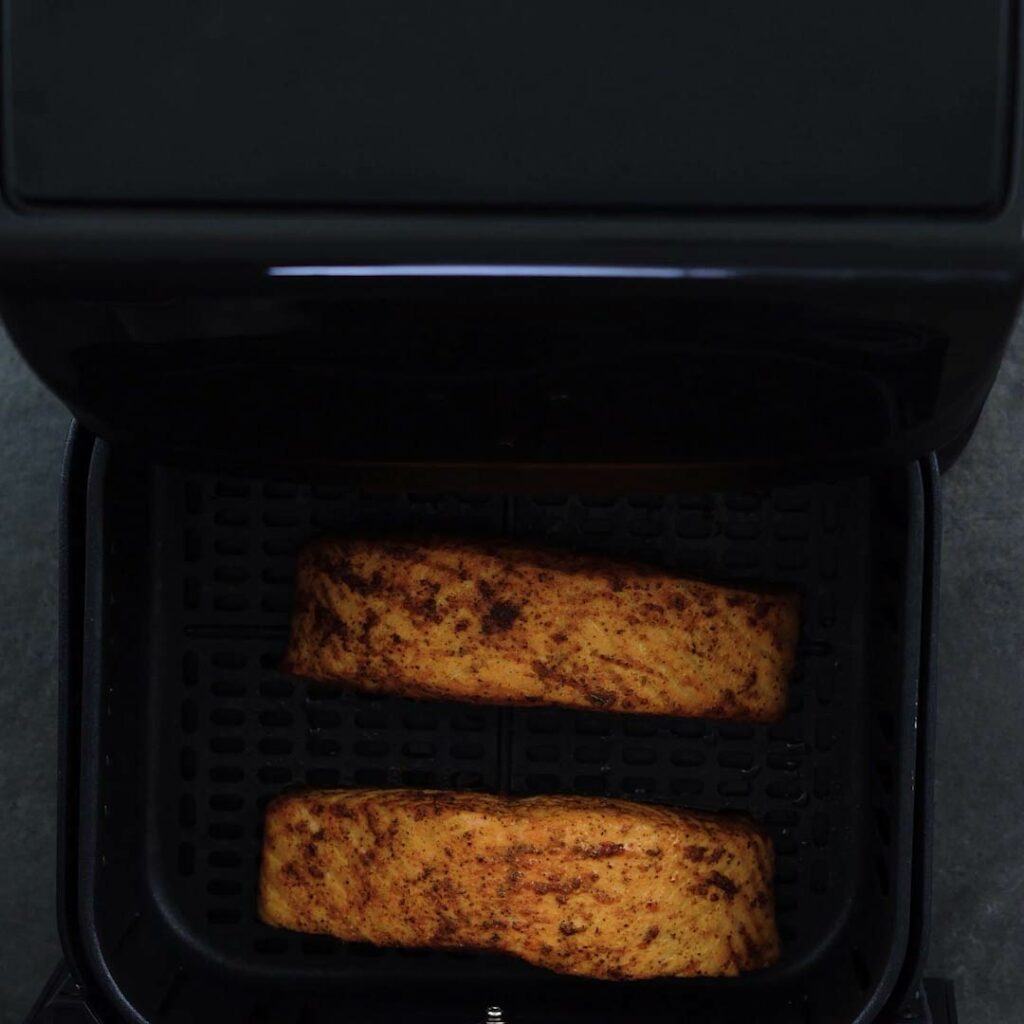Perfectly air fried salmon in the air fryer basket.