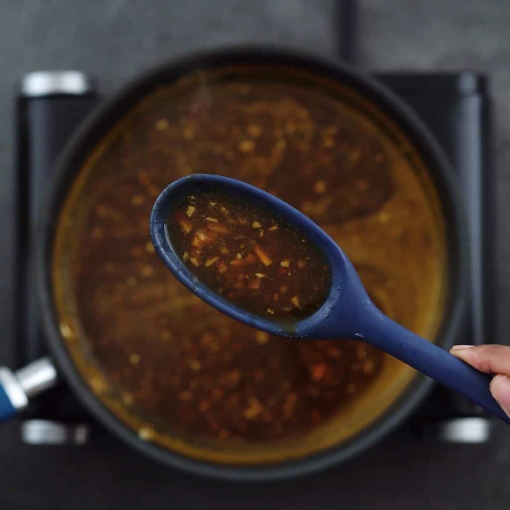 Showing thick orange sauce mixture in a spoon.
