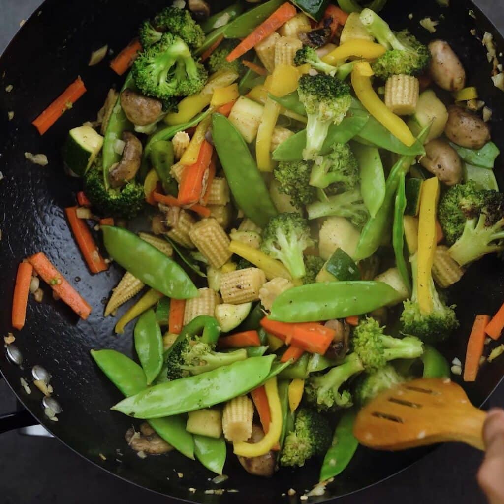 Stir frying the vegetables using a wooden spatula.