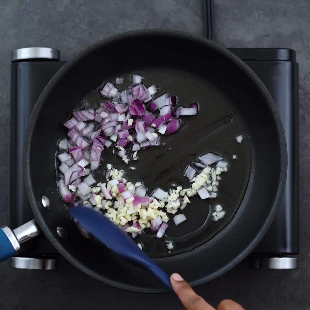 Sautéing onions and garlic in a frying pan.
