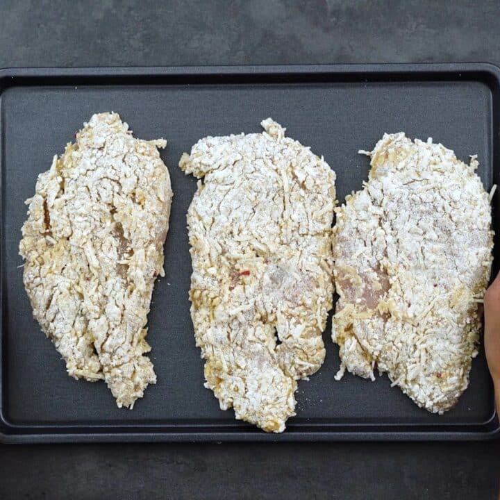 Breaded chicken breast in a baking tray.