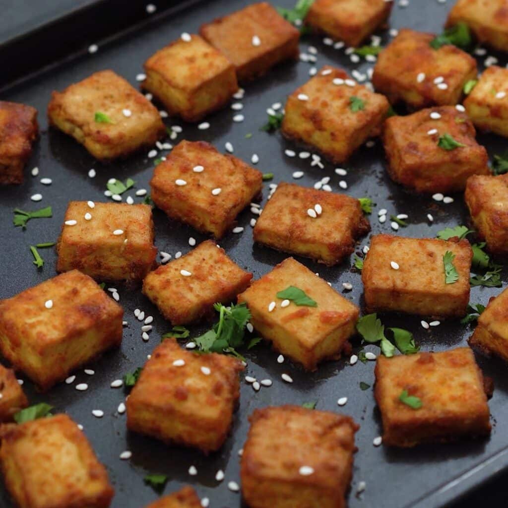 Crispy baked tofu served in a black baking tray.
