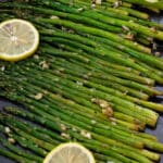 Based Asparagus in a in baking tray with lemon slices.