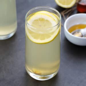 Ginger Lemon Water in a glass with few ingredients around.