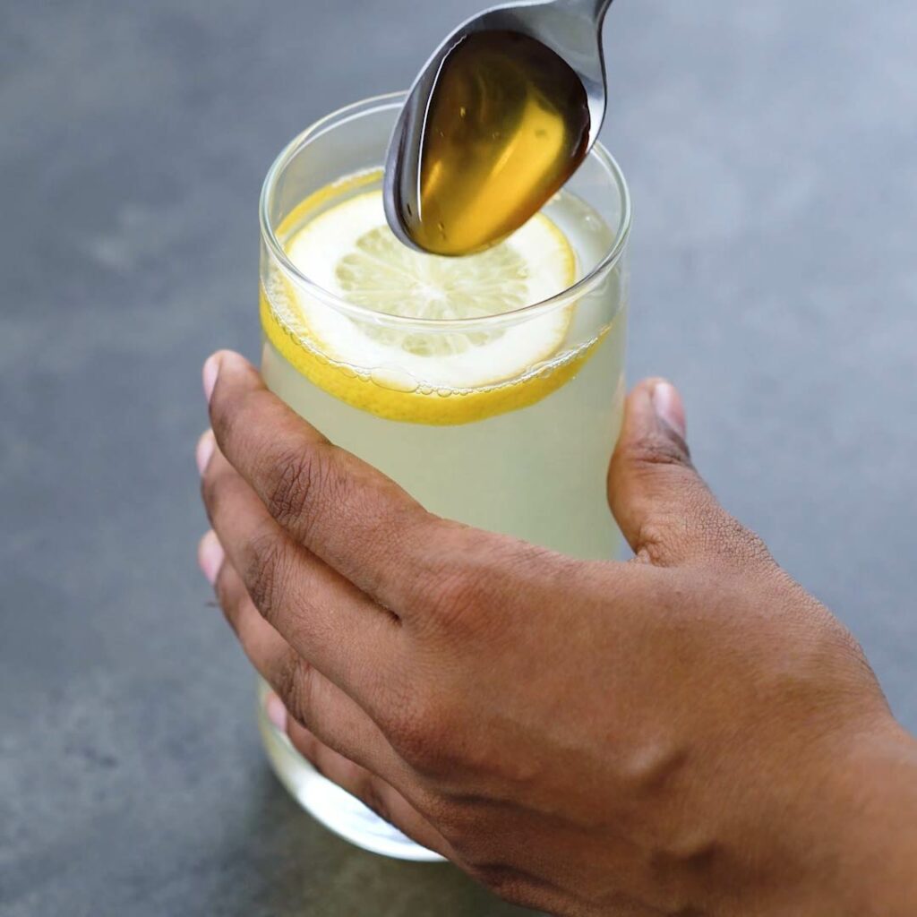Adding honey to ginger lemon water.