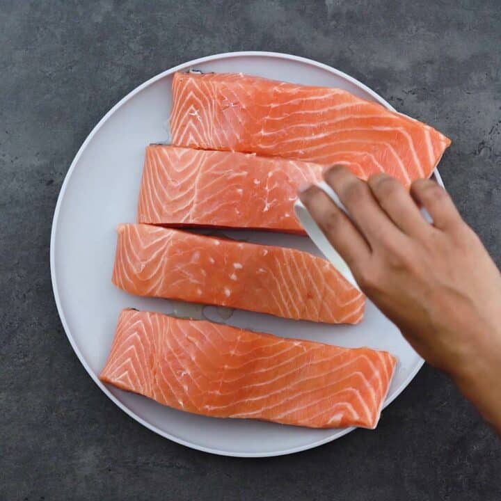 Pouring oil over salmon fillets.