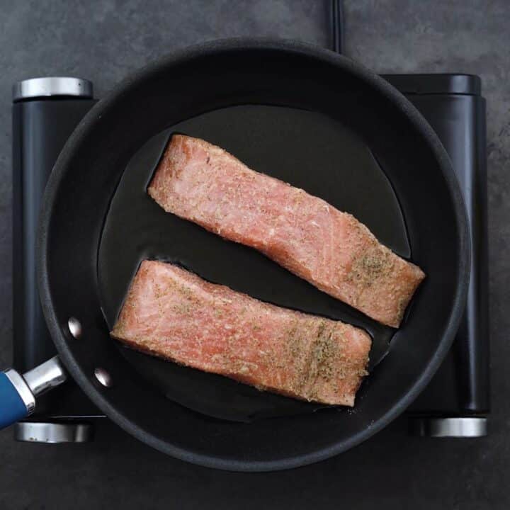 Salmon fillets placed in a frying pan.