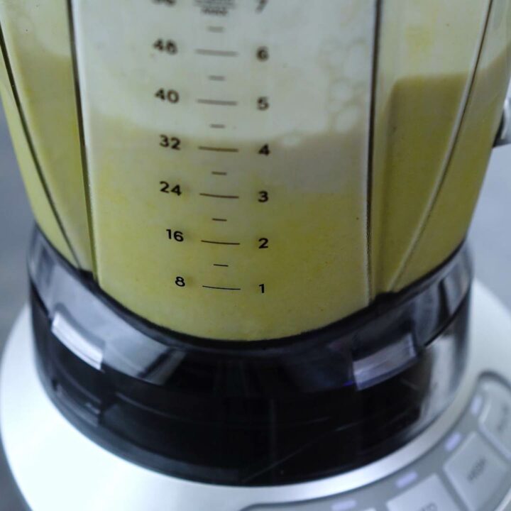 Ingredients for peach smoothie is being blended in a blender.