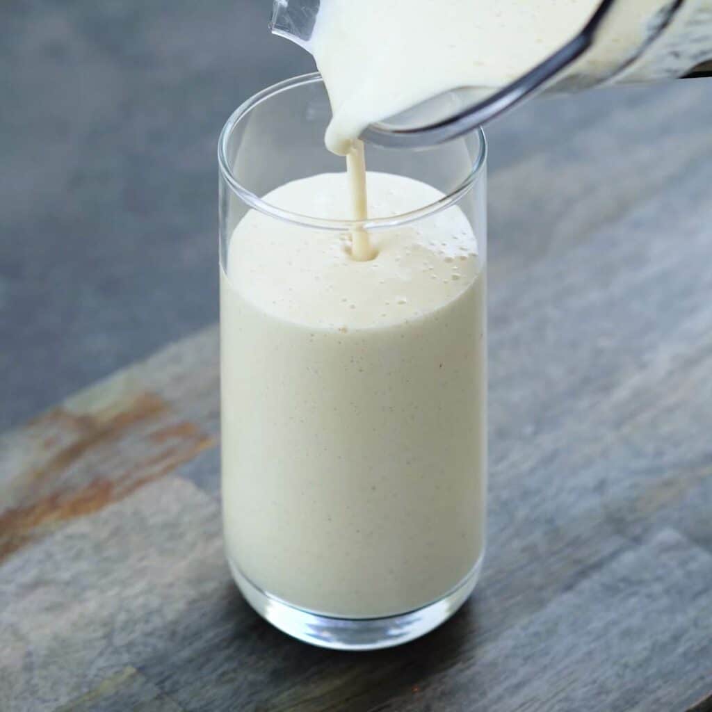 Pouring Peach Smoothie into a serving glass.