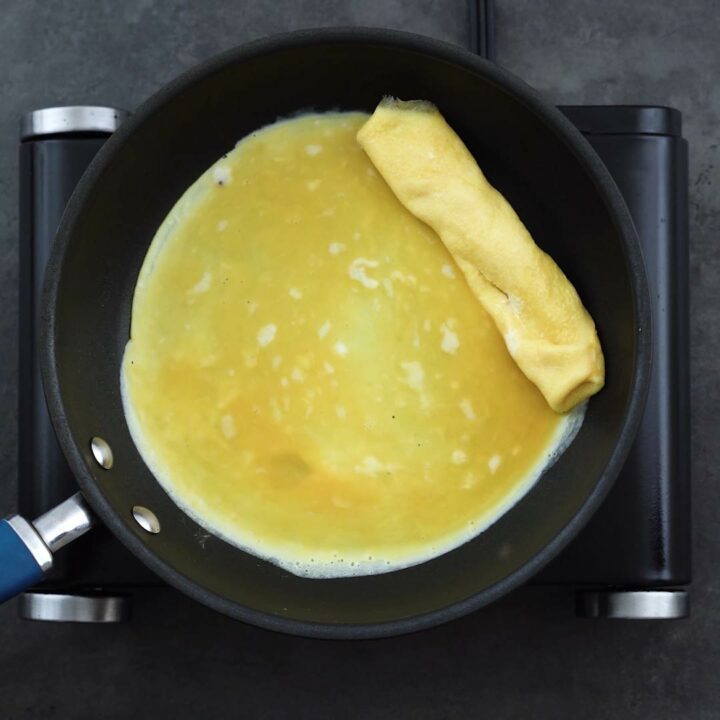 Rolled egg and a thin layer of egg mixture in the pan.