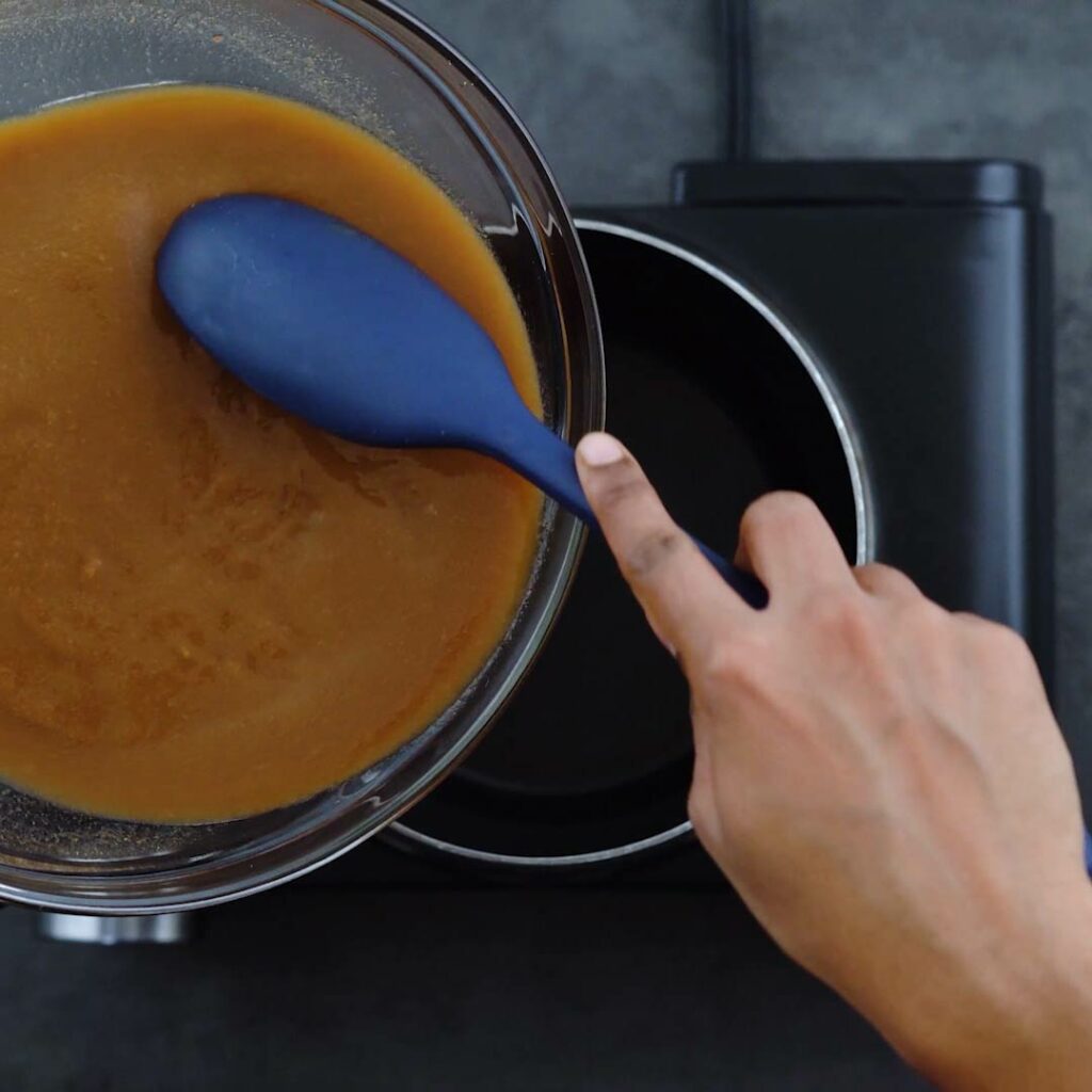 Pouring the tamarind pulp into the saucepan.