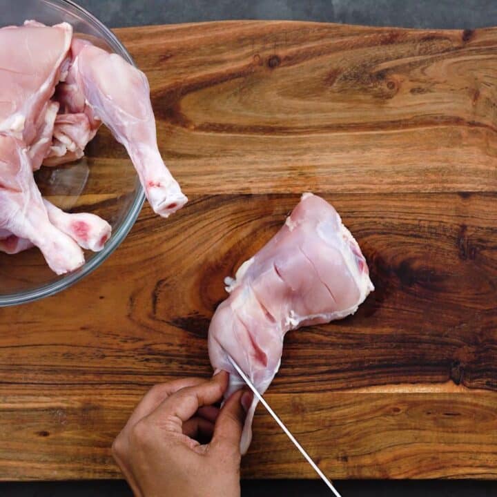 Making slits on Chicken leg quarters using a knife.