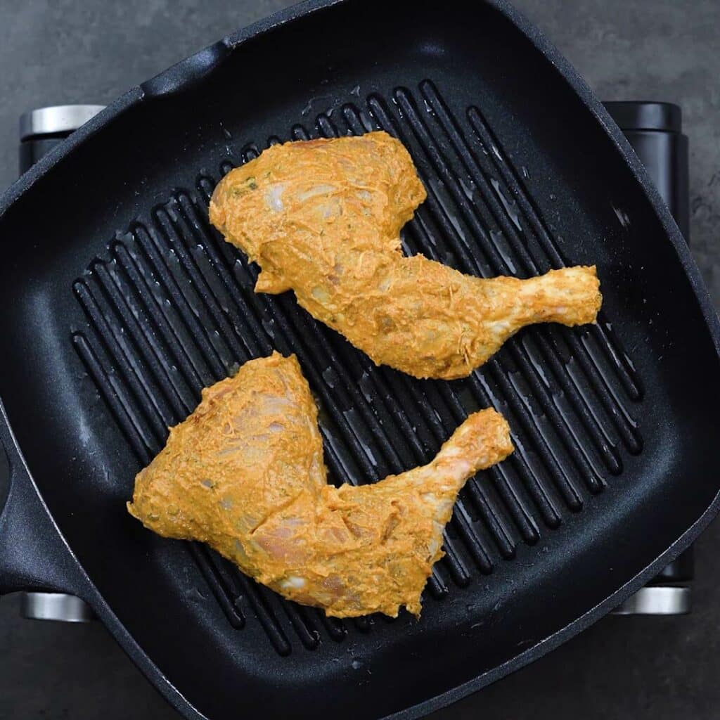 Marinated Chicken Leg Quarters on a grilling pan.