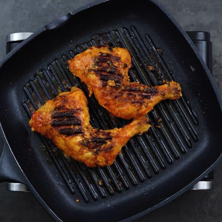 Chicken Leg Quarters grilling in a pan.