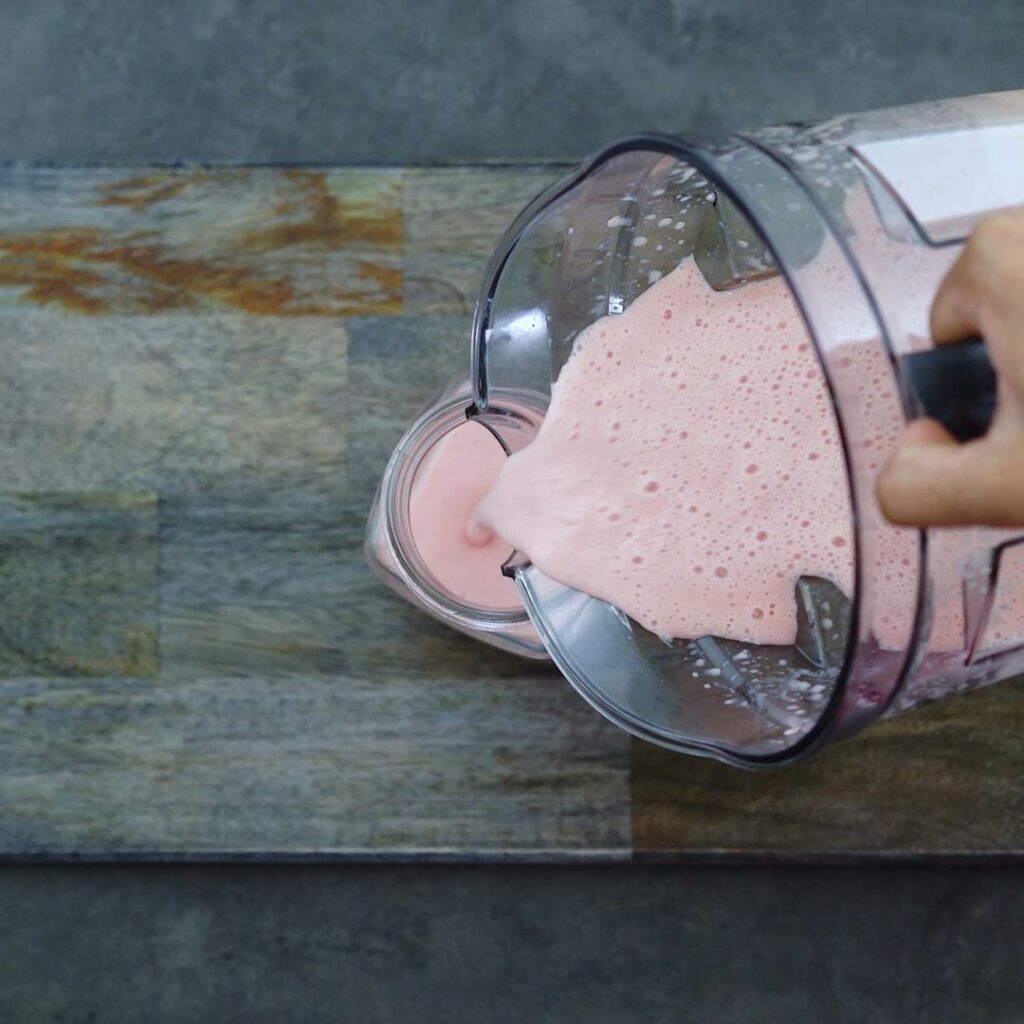 Pouring Watermelon Strawberry Smoothie into a serving mug.
