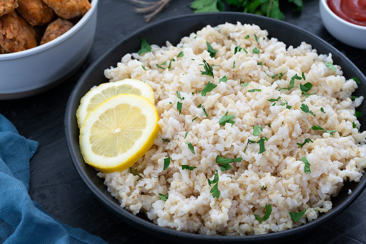 Brown Rice in a black bowl with lemon slices.