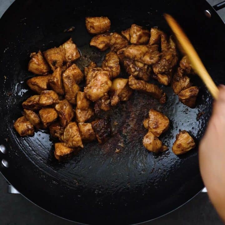 Stir frying the chicken in a wok.