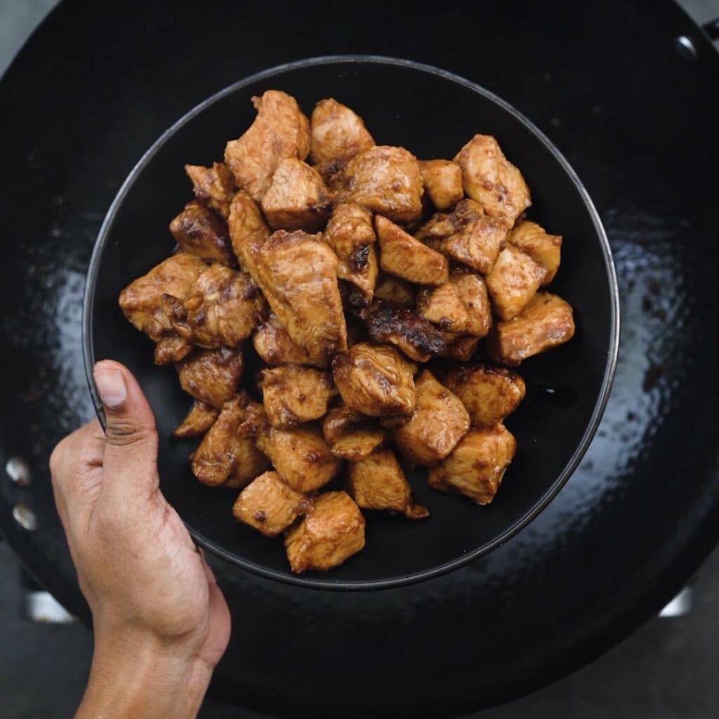 Stir Fried chicken in a black plate.