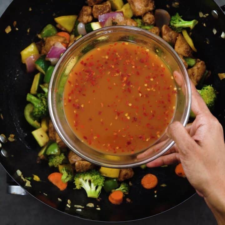 Adding stir fry sauce into stir fried chicken and vegetable.