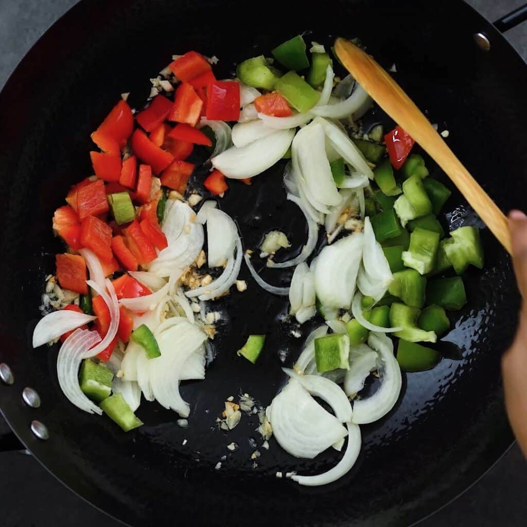 Stir frying the bell peppers and onions.