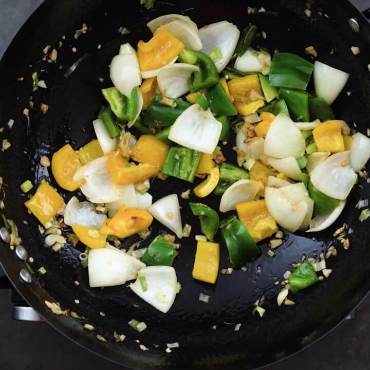 Bell peppers and onions along with other aromatics in the wok.