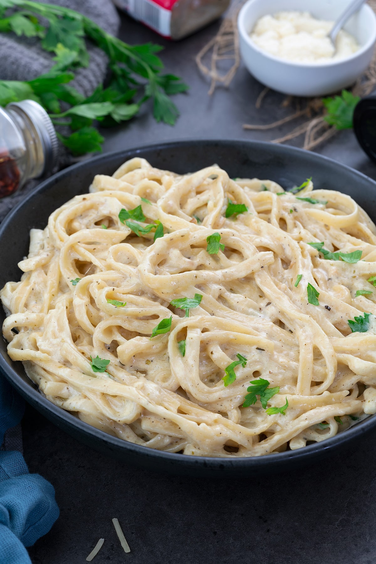 Fettuccine Alfredo Pasta in a black bowl placed on a grey table.