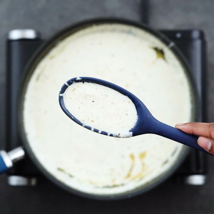 Showing the consistency of Alfredo Sauce in a blue spoon.