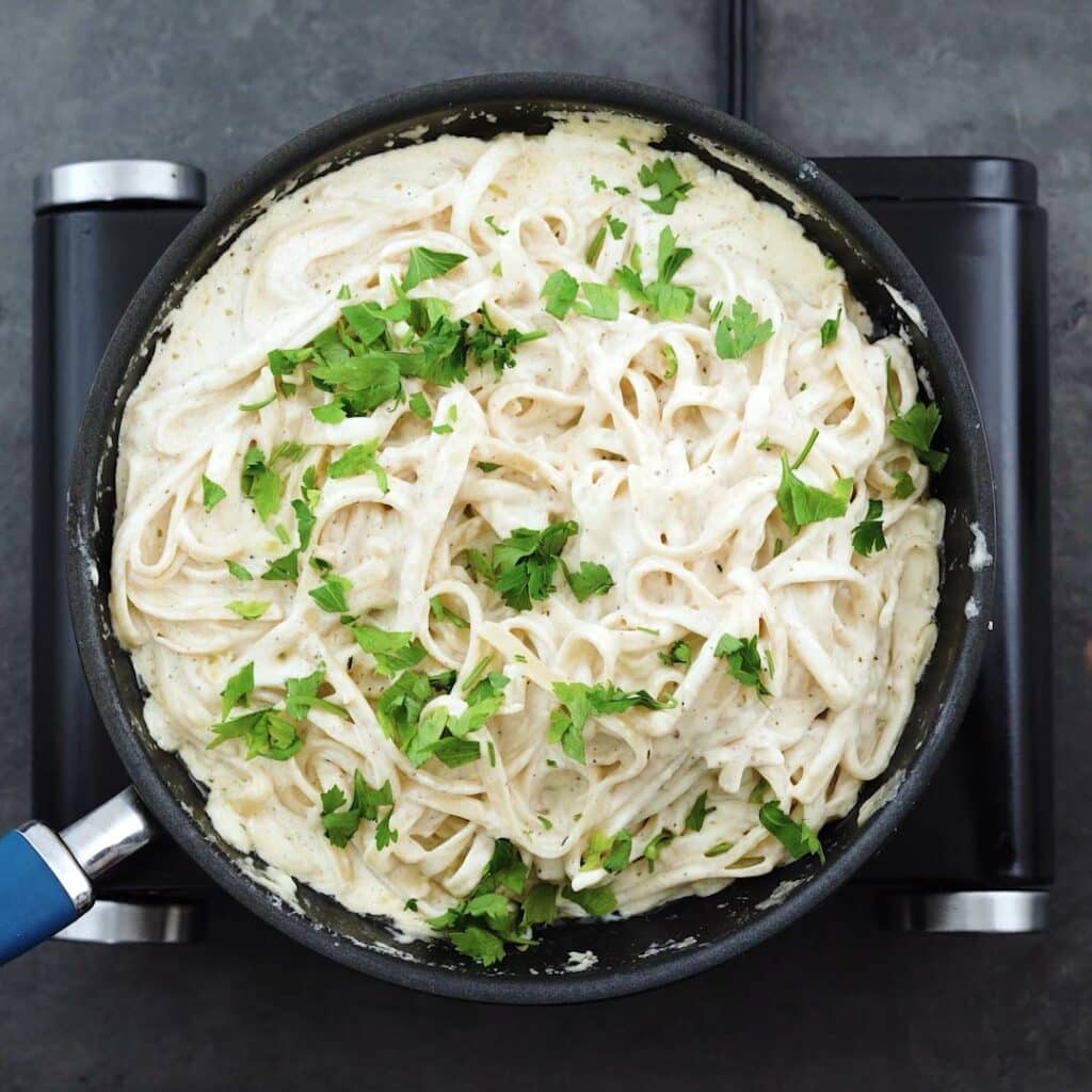 Fettuccine Alfredo garnished with parsley leaves.