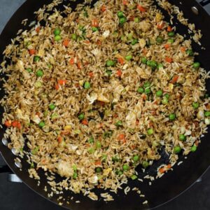 Fried rice garnished with green onions in a wok.