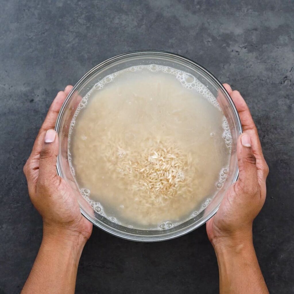 Brown rice with water in a glass bowl.