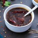 Stir fry sauce in a white bowl on a grey table with few ingredients around.