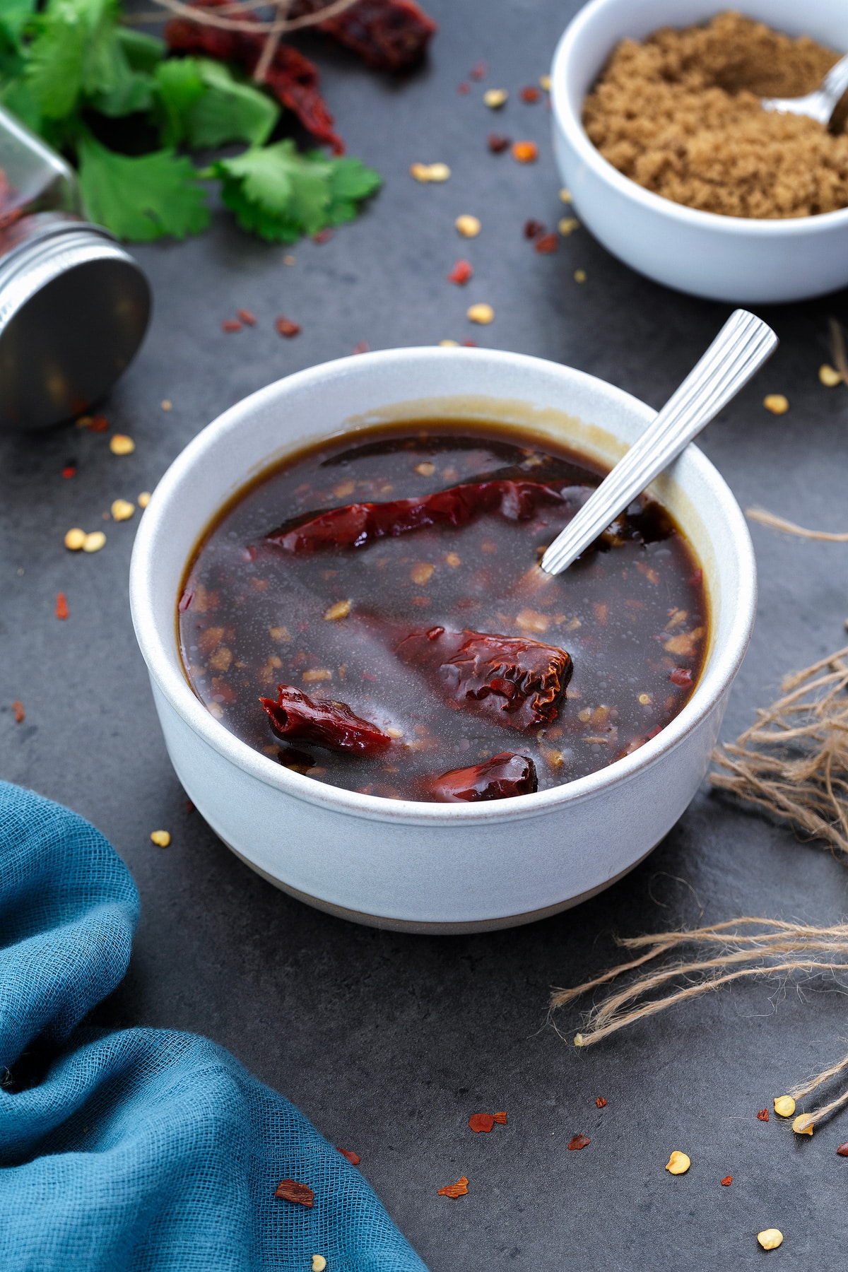 Stir fry sauce in a white bowl on a grey table with few ingredients around.