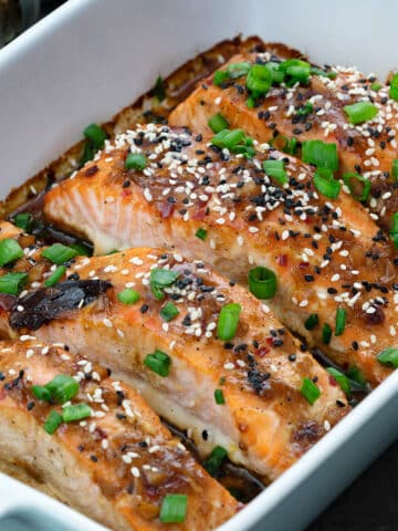 Teriyaki Salmon fillets in a ceramic baking tray with few ingredients around.