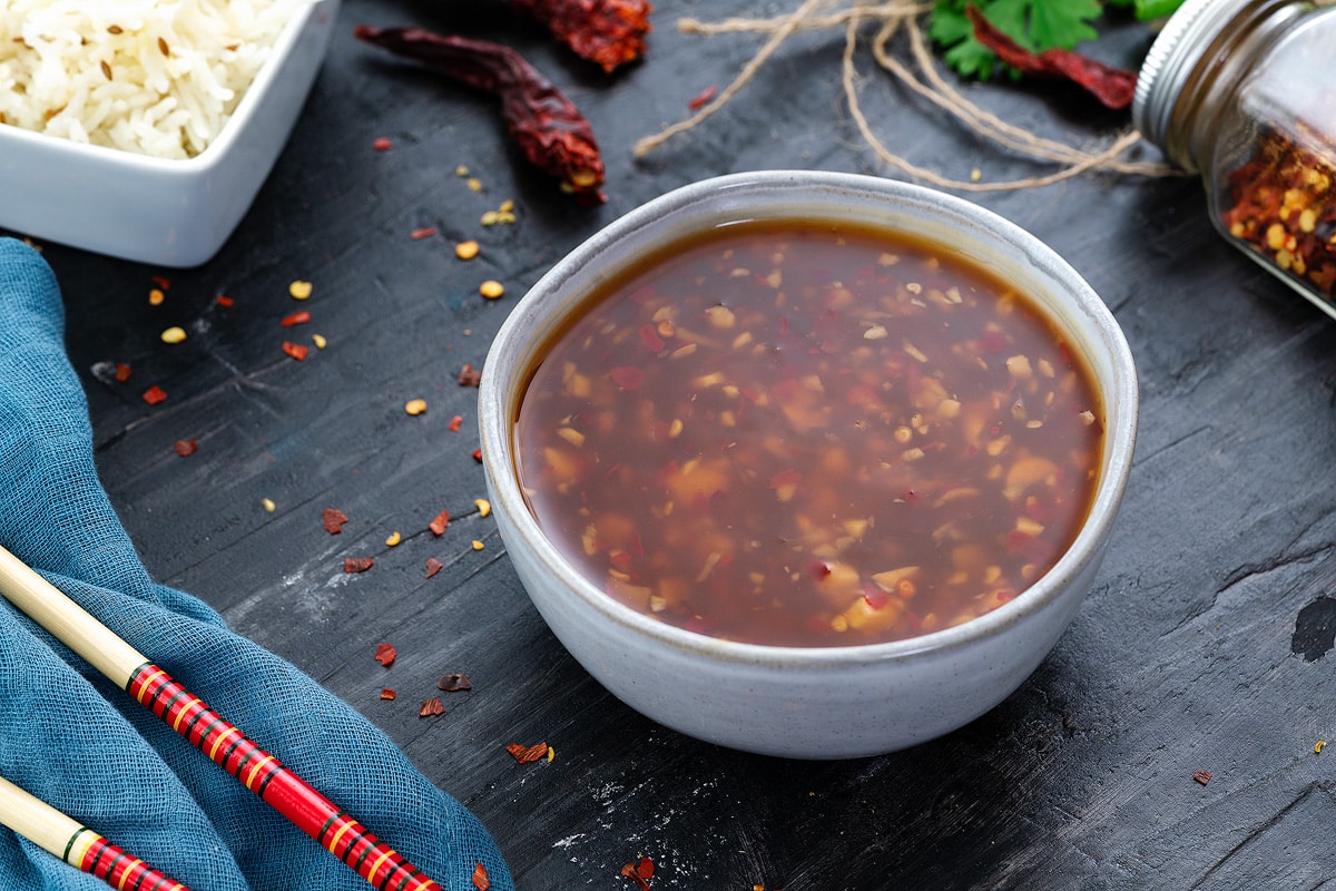 Thai Sweet Chili Sauce in a white bowl with few ingredients around.