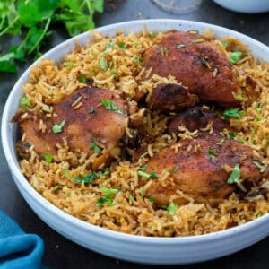 Chicken and Rice in a white bowl on a grey table with few ingredients around.