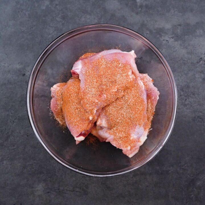 Chicken thighs are sprinkled with seasoning powder.