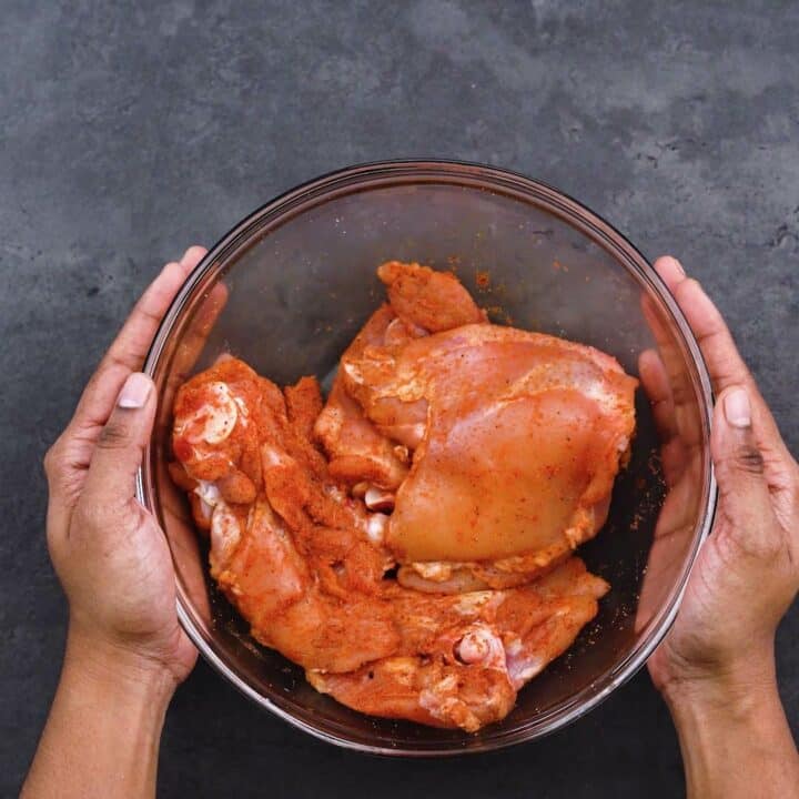 Seasoned chicken thighs in a glass bowl.