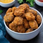 Crispy Homemade chicken nuggets in a white bowl with few ingredients around.