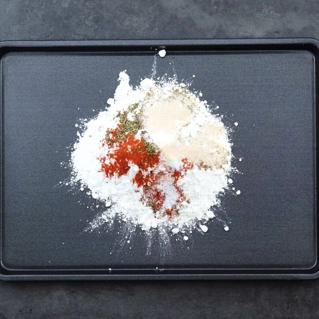 Flour mixture with seasonings in a tray.