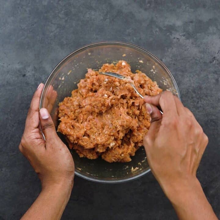 Mixing ground chicken with seasonings.