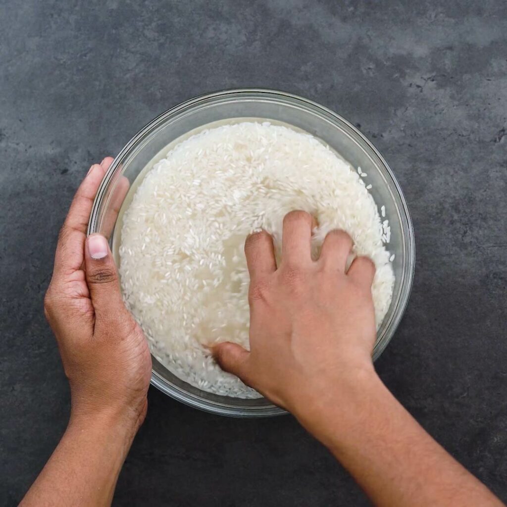 Rinsing rice with water in a bowl.