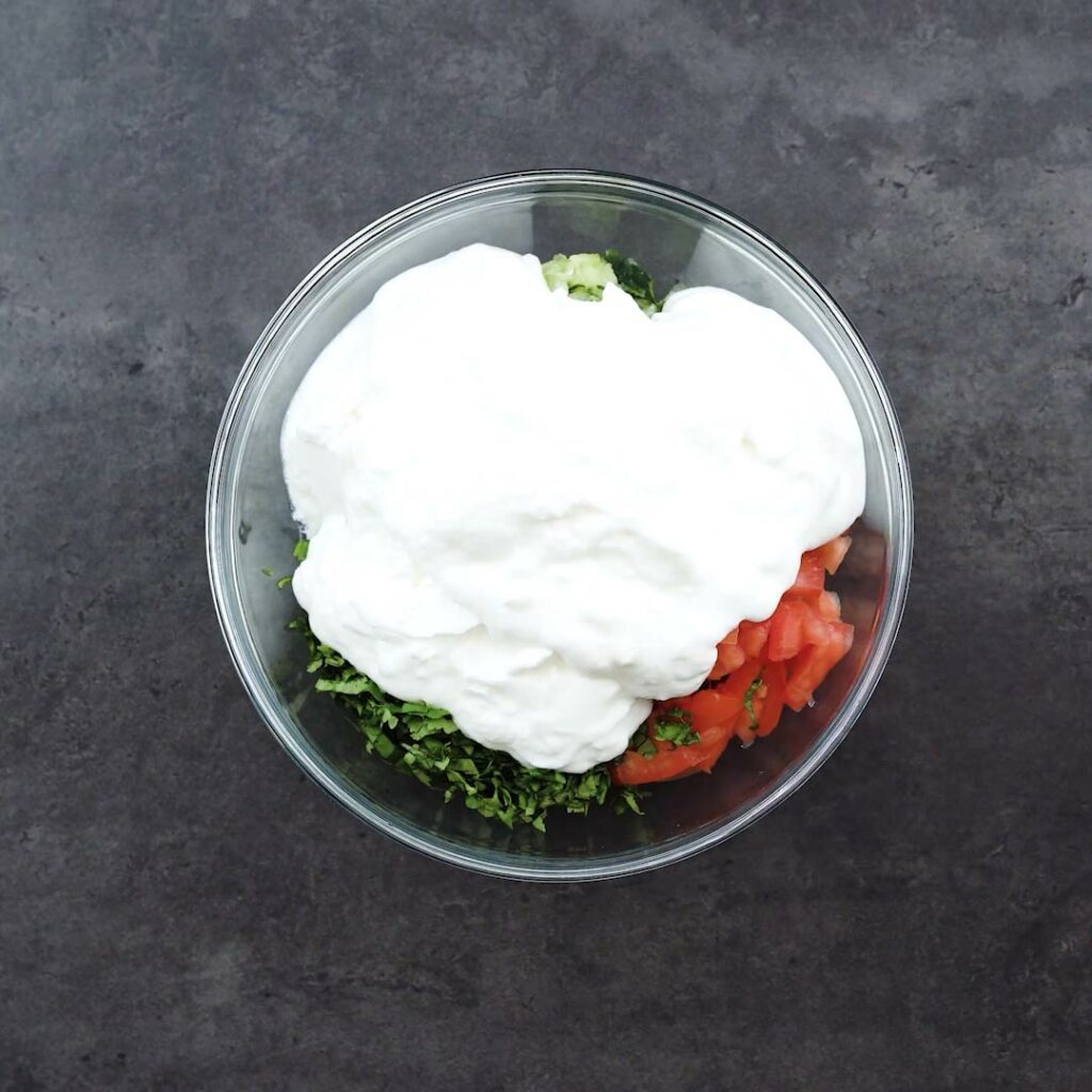 Yogurt and vegetables in a glass bowl.