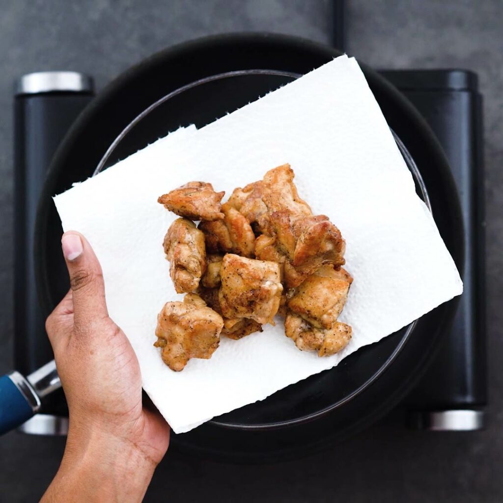 Fried chicken thighs on a black plate placed on a tissue paper.