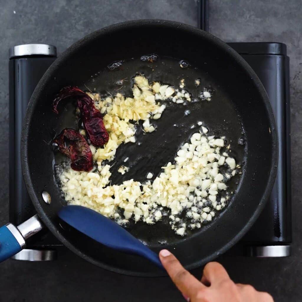 Sauteing the aromatics in a frying pan.