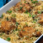 Baked chicken and rice in a baking tray with few ingredients around.