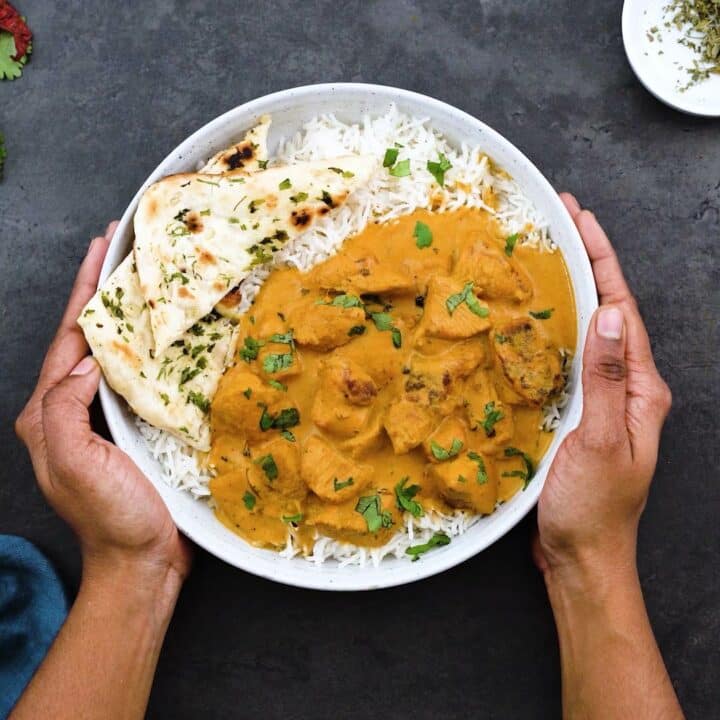 Serving Butter chicken curry over basmati rice and naan alongside.
