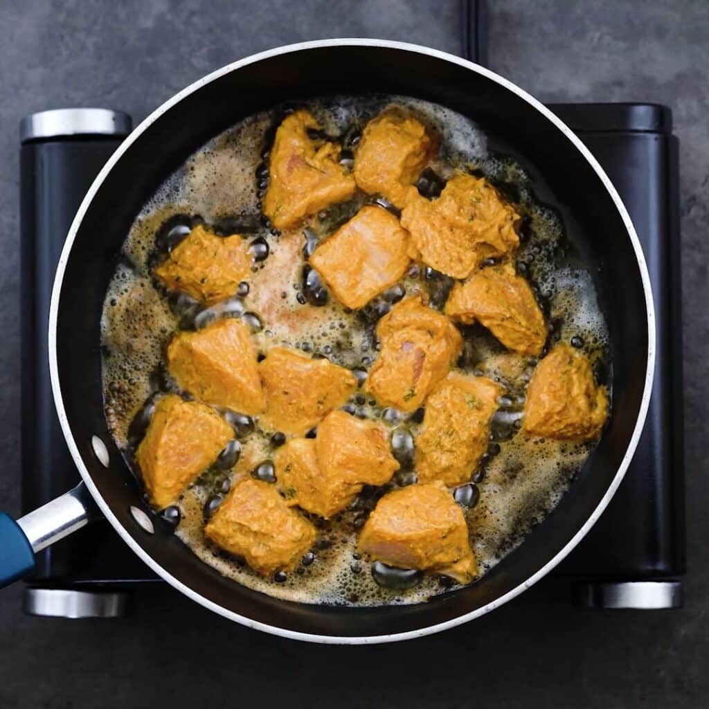 Frying marinated chicken in a pan.