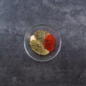 A bowl with spice powders and dried herbs.
