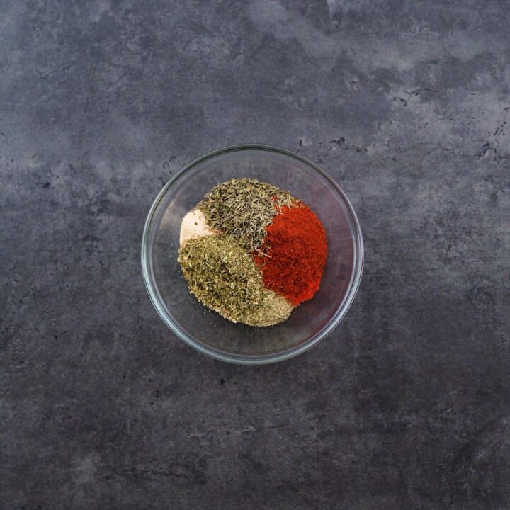 A bowl with spice powders and dried herbs.